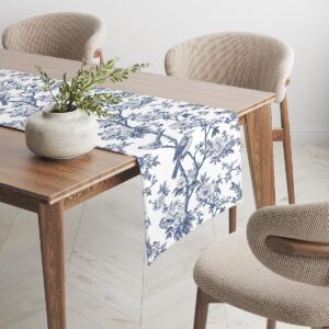 Bieżnik rozłożony na drewnianym stole z wazonem i krzesłami w tle