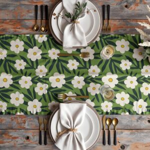 Widok z góry na stół nakryty bieżnikiem z białymi kwiatami i zastawą, aranżacja stołu