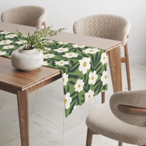 Bieżnik z białymi kwiatami rozciągnięty na stole w jadalni z krzesłami i dekoracją ze świeżych gałązek