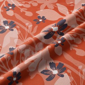 Zbliżenie na tkaninę pokazujące detale nadruku i granatowe kwiaty na ceglastym tle