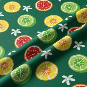Detal tkaniny z nadrukiem plasterków cytrusów i białych kwiatków na zielonym tle