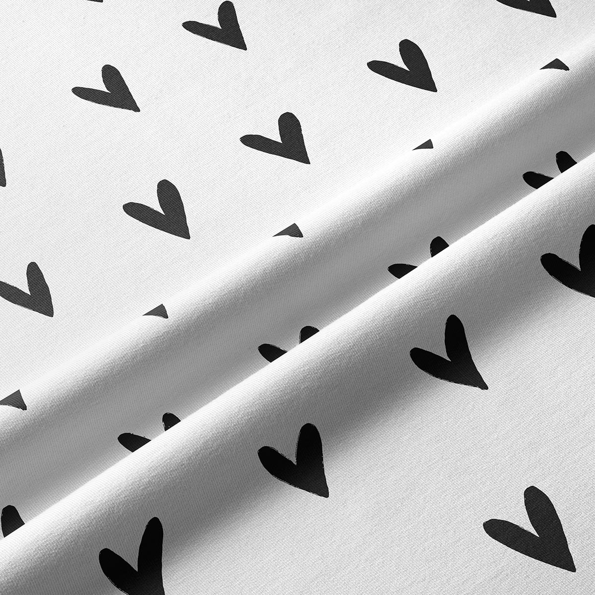 Zbliżenie na tkaninę z czarnymi serduszkami, widoczna faktura materiału