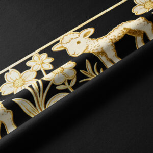 Zbliżenie na tkaninę: złoty nadruk baranka i drobnych kwiatów na czarnym tle