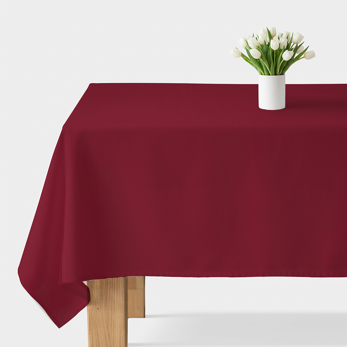 gładki bordowy obrus na stole z białym wazonem i tulipanami