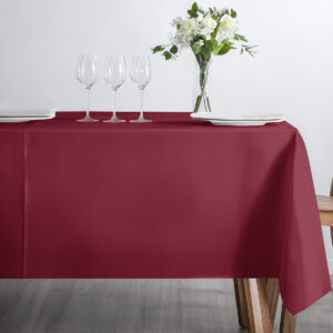 prostokątny stół nakryty bordowym obrusem z kieliszkami i bukietem kwiatów