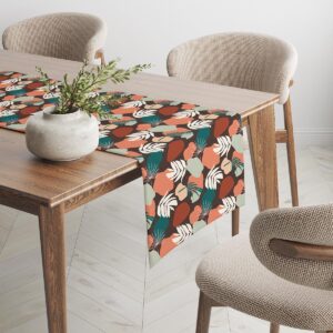 Bieżnik rozciągnięty wzdłuż stołu, powtarzający się wzór liści i kolorowych plam