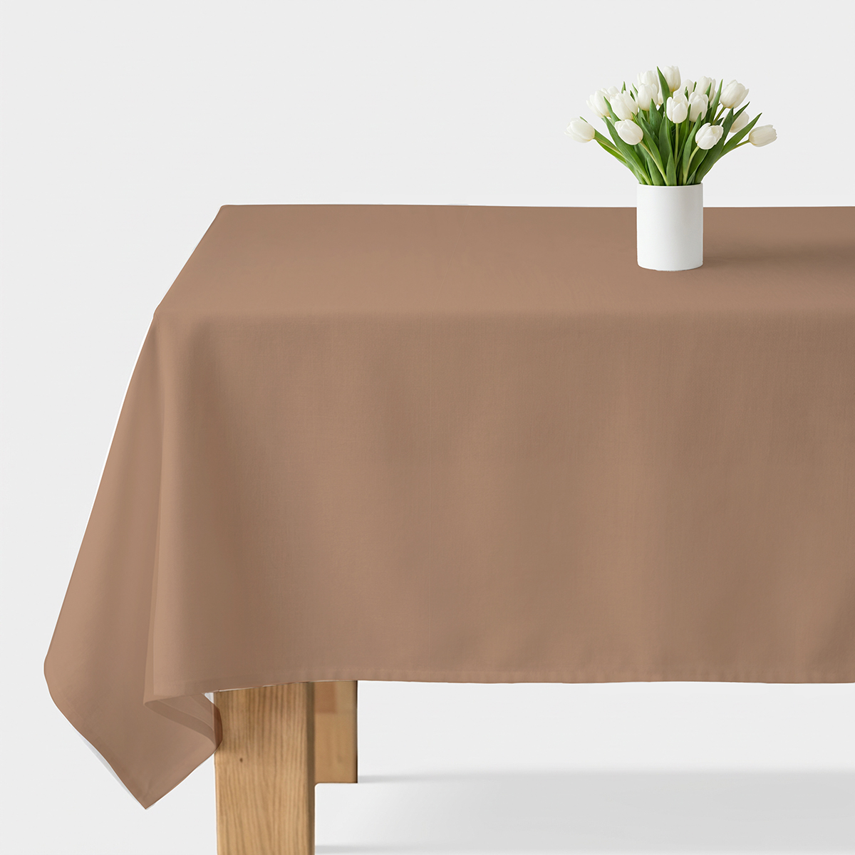 obrus gładki w karmelowym odcieniu na stole z wazonem białych tulipanów