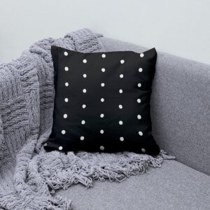 Poduszka ozdobna z groszkami ułożona na szarej sofie z kocem, stylizacyjne ujęcie