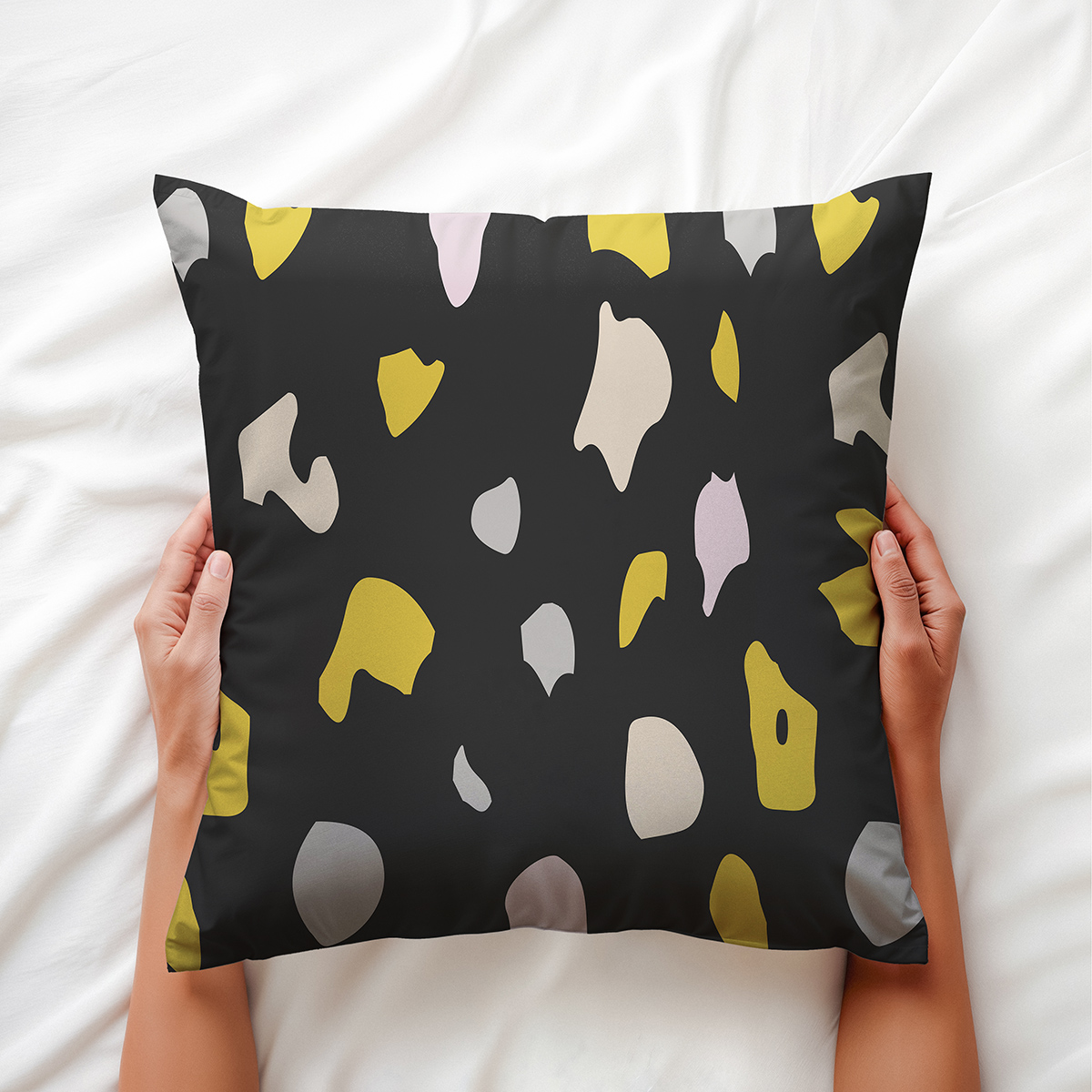 Górne ujęcie poduszki trzymanej w dłoniach, widoczne nieregularne plamy i struktura tkaniny