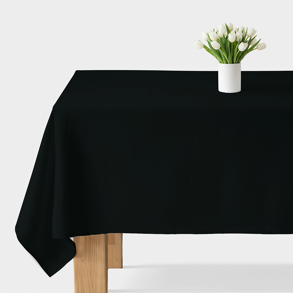 gładki czarny obrus na stole z białym wazonem tulipanów