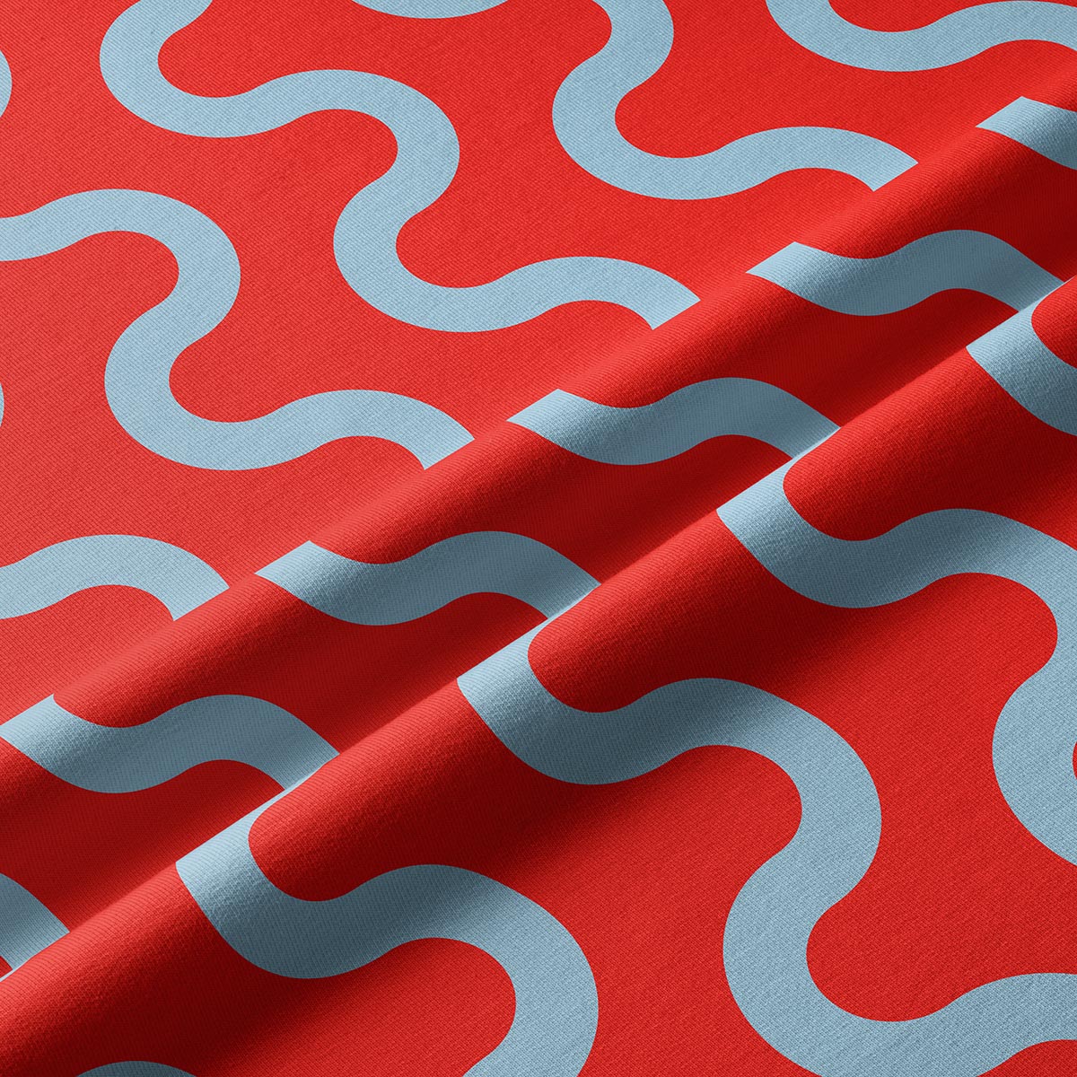 Zbliżenie na tkaninę pokazujące fakturę materiału i błękitne fale na czerwonym tle