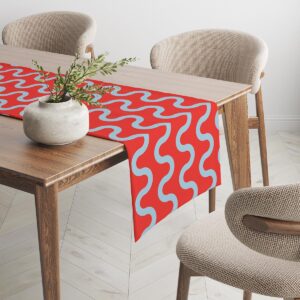 Widok z boku bieżnika leżącego na stole, powtarzający się falisty motyw na czerwonym tle