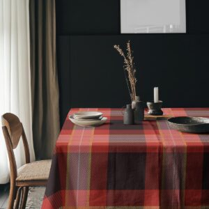 Aranżacja stołu z naczyniami i suchymi dekoracjami na kraciastym obrusie w ciepłych odcieniach