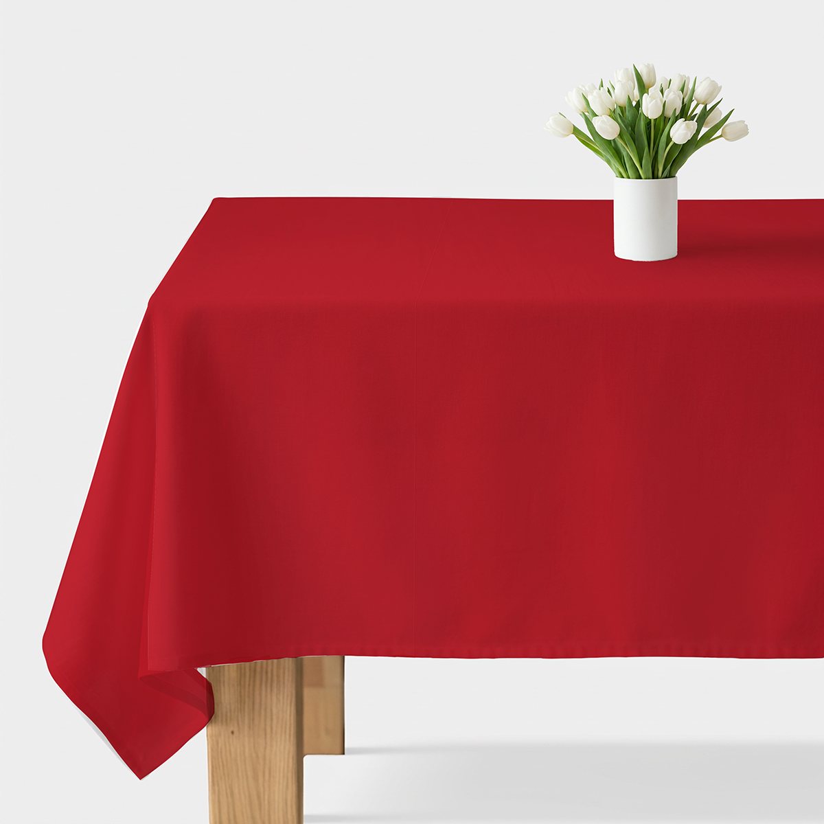 gładki czerwony obrus rozłożony na stole z białym wazonem z tulipanami
