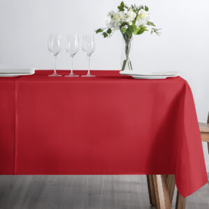 frontowe ujęcie stołu z czerwonym obrusem, kieliszkami i wazonem z kwiatami