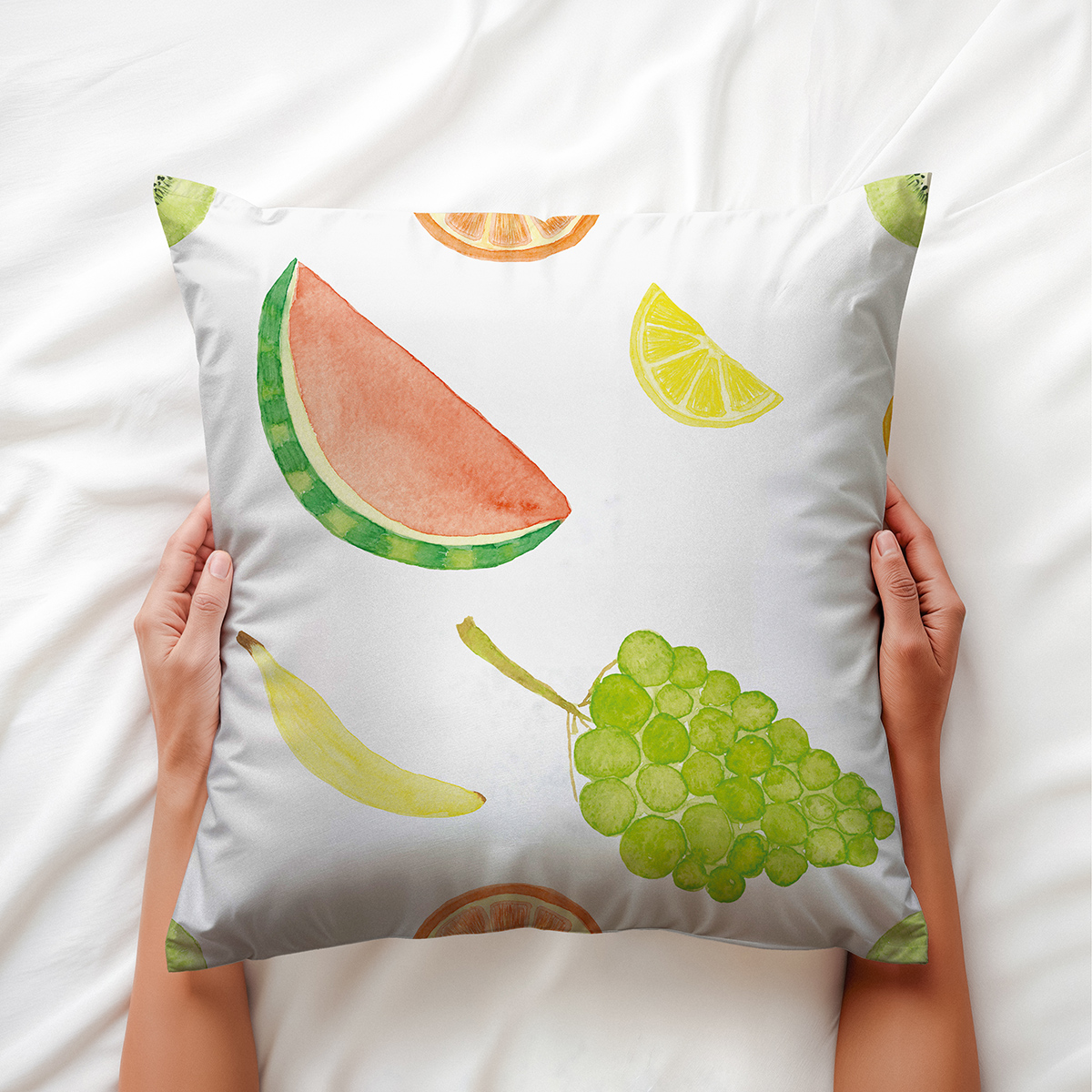 Poduszka trzymana w dłoniach na łóżku, widoczne detale akwarelowego arbuza i winogron