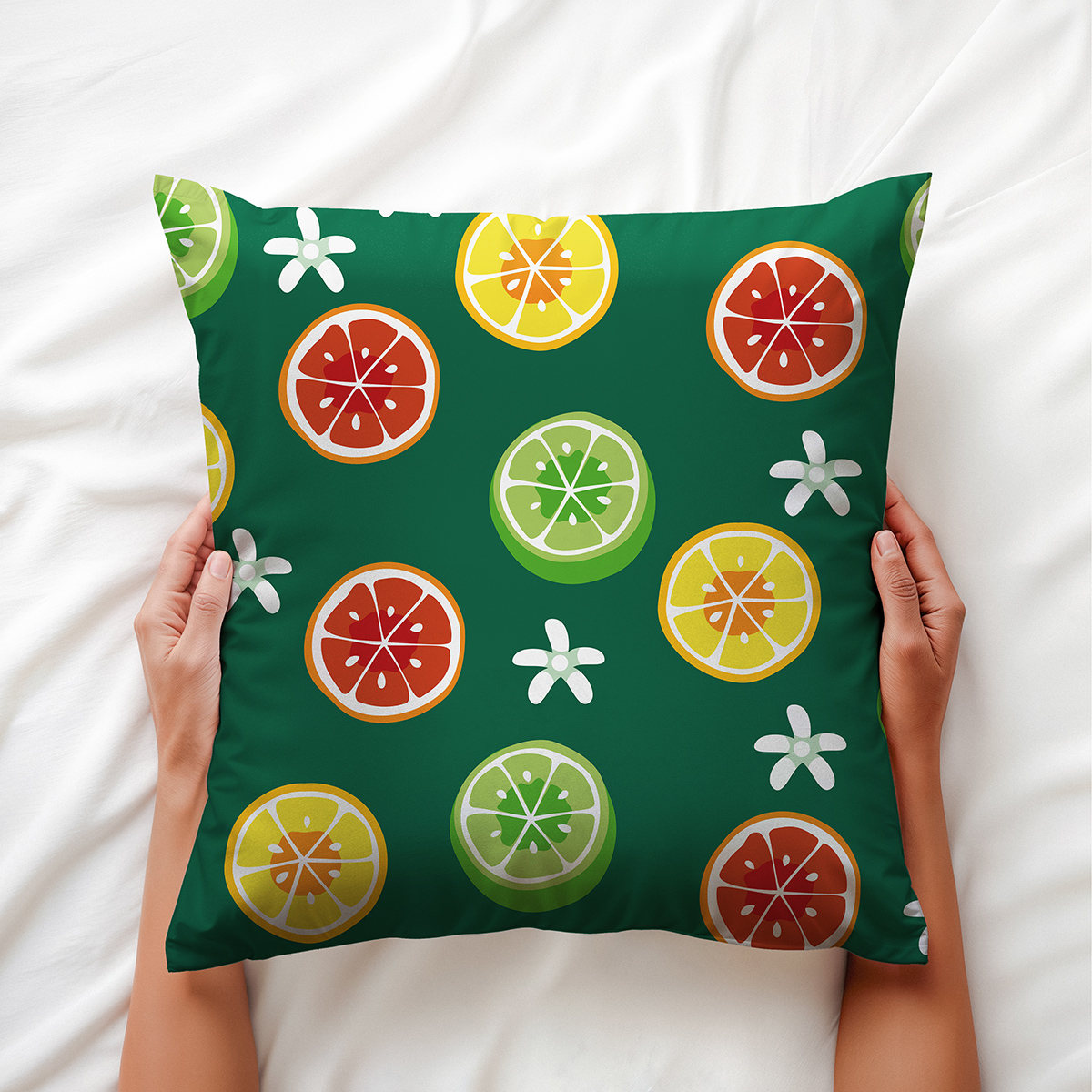 Ręce trzymające poduszkę z kolorowymi plasterkami cytrusów na tle białej pościeli