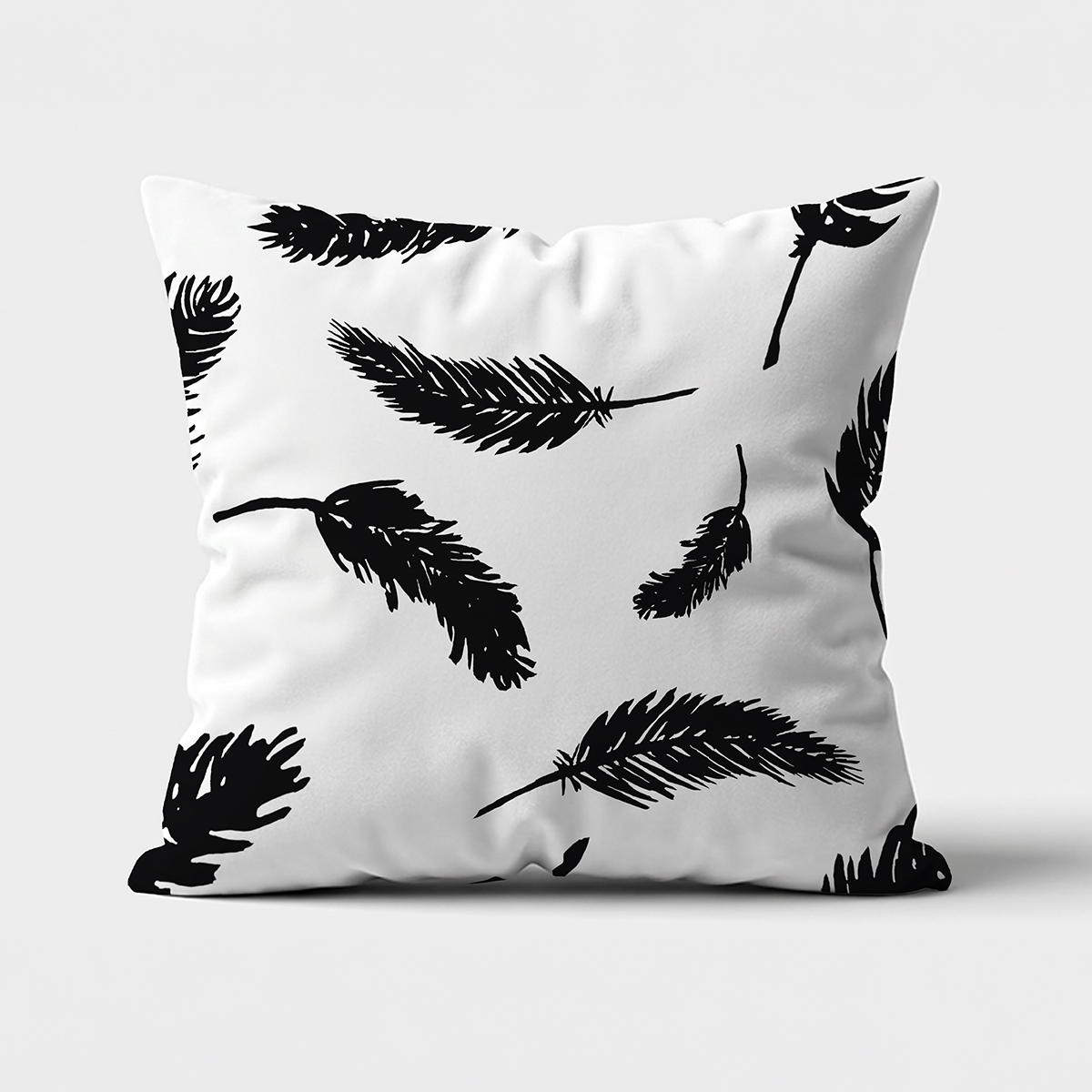Poduszka dekoracyjna z czarnymi graficznymi piórami na białym tle, widok z przodu