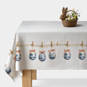 obrus z motywem porcelanowych pisanek i koronką na stole, widoczny wiklinowy koszyk z dekoracyjnymi jajkami