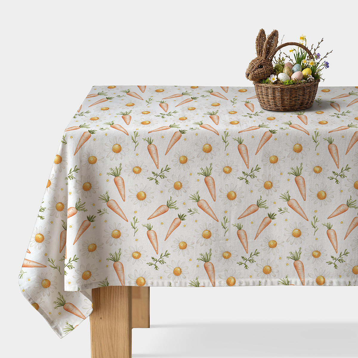 Świąteczny obrus z wzorem marchewek i stokrotek, widok stołu z koszykiem wielkanocnym