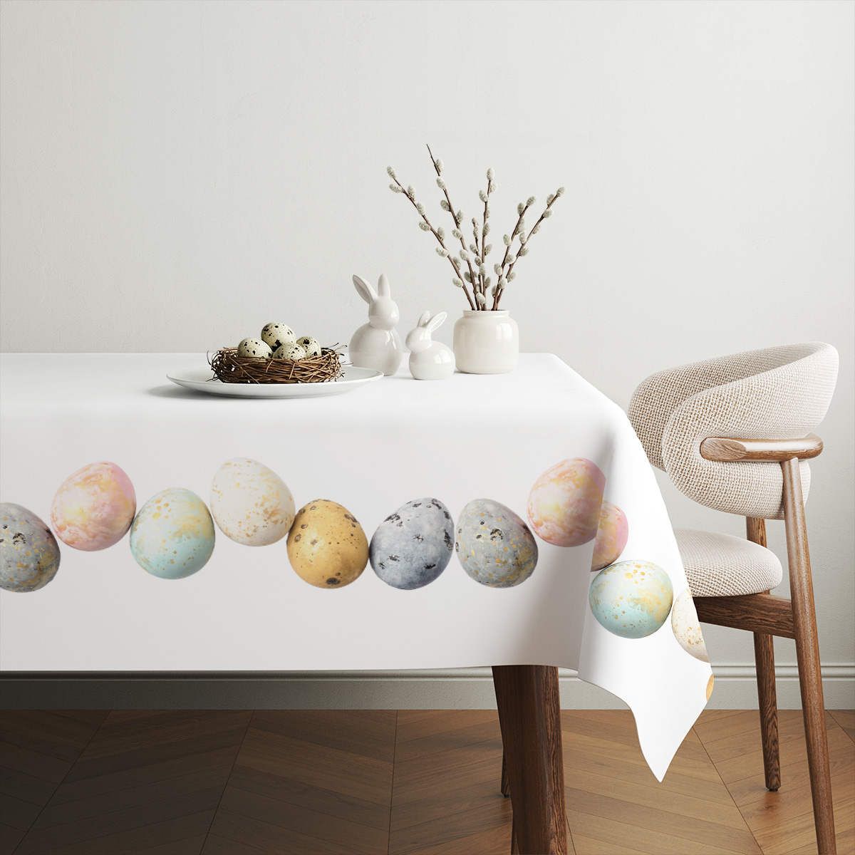 Aranżacja stołu z białymi dekoracjami i subtelnym, świątecznym obrusem z motywem pisanek