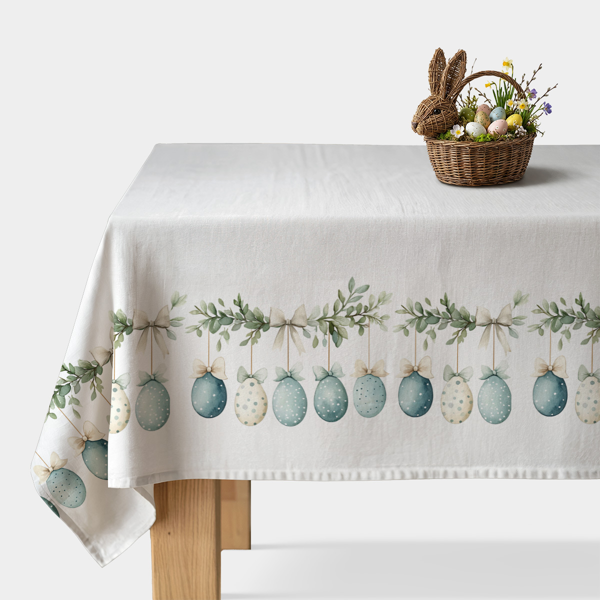 obrus z zawieszonymi akwarelowymi pisankami i zielonymi gałązkami, widok na środek stołu