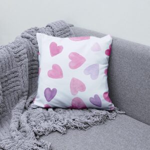 Poduszka ozdobna z akwarelowymi sercami na szarej sofie obok pledu