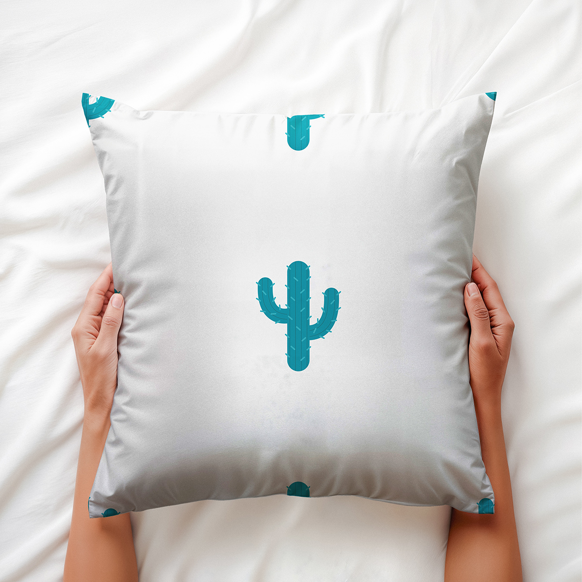 zbliżenie na poduszkę trzymaną w dłoniach pokazujące wzór turkusowego kaktusa
