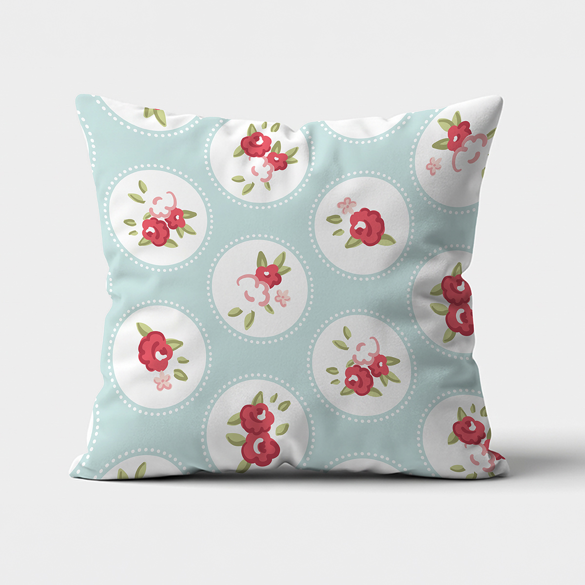 Poduszka dekoracyjna na miętowym tle z różowymi kwiatowymi medalionami, widok frontalny