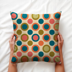 Widok z góry na poduszkę trzymaną w rękach, pokazujący kolorowe koncentryczne kropki i fakturę materiału