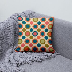 Poduszka ozdobna ułożona na kanapie obok pledu, prezentująca motyw retro i zestawienie kolorów