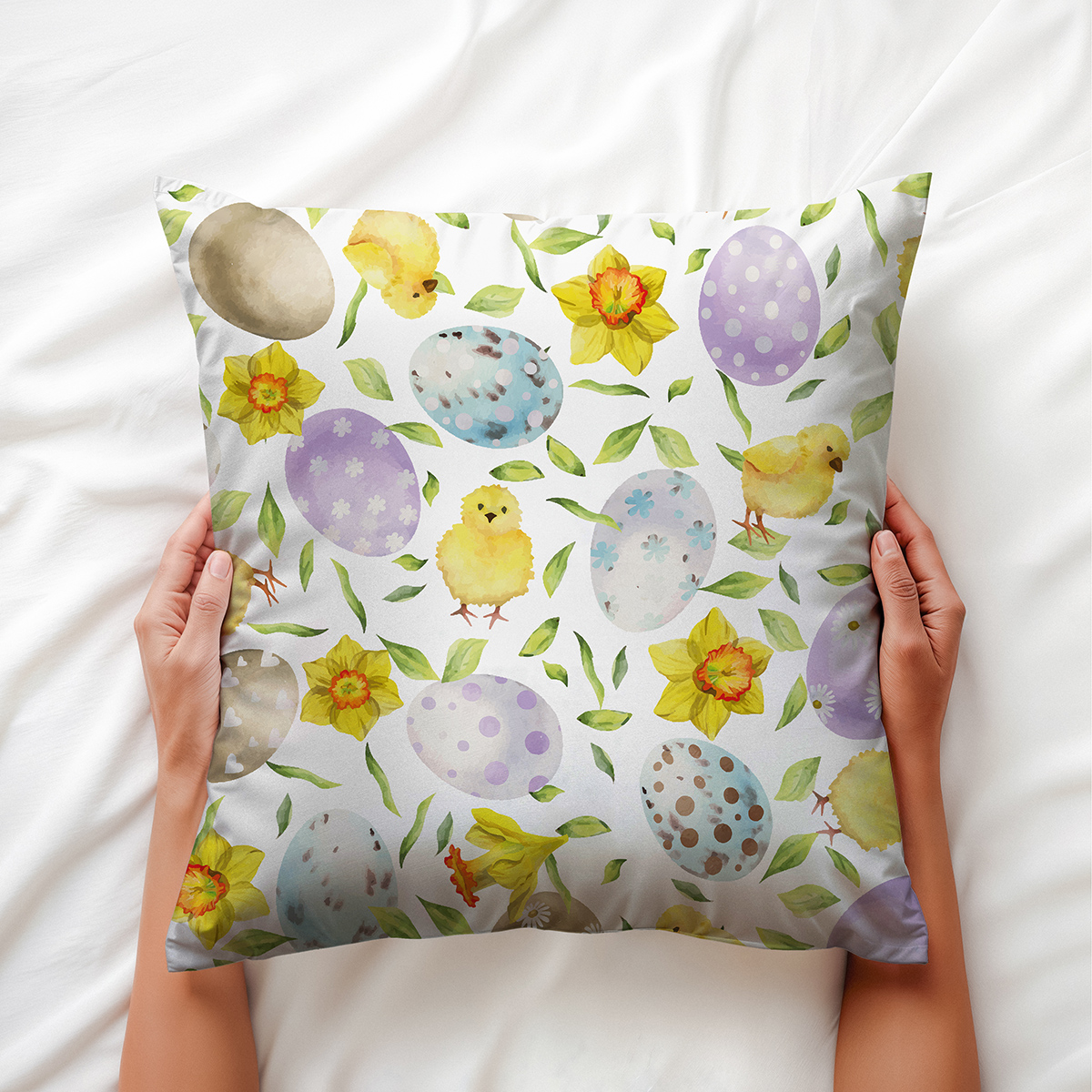 Dłonie trzymające poduszkę z wiosennym motywem pisanek i żonkili