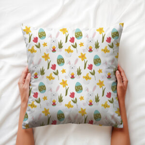 Widok poduszki z góry trzymanej w dłoniach, ukazujący rozmieszczenie zajączków i pisanek