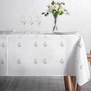 minimalistyczne ustawienie z talerzami i kieliszkami na obrusie w drobne listki i kropki