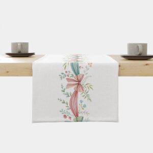 Bieżnik ułożony na stole z centralnym pasem pastelowych wstążek i gałązek