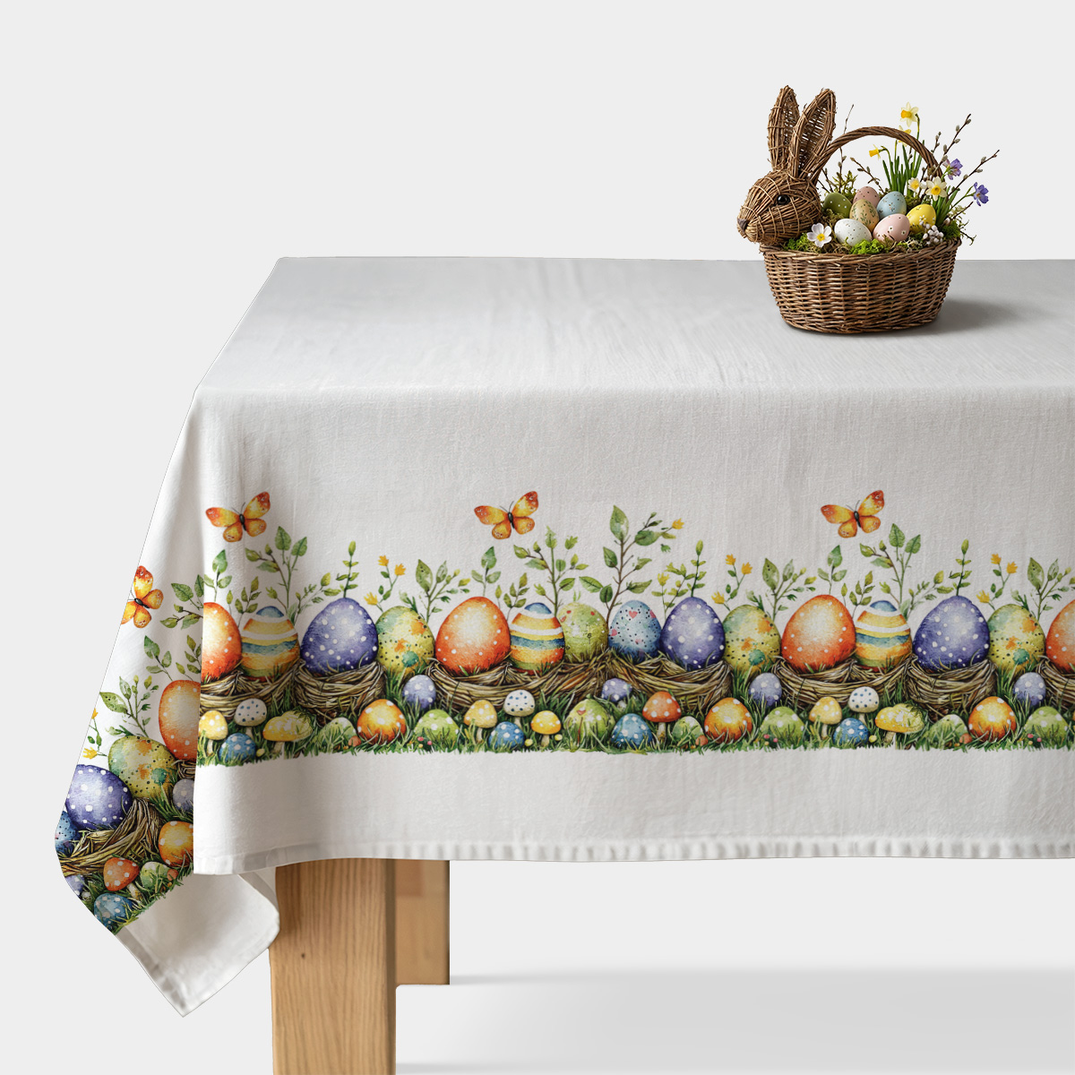 biały obrus z kolorowym brzegiem pisanek w gniazdkach i motylkiem na stole