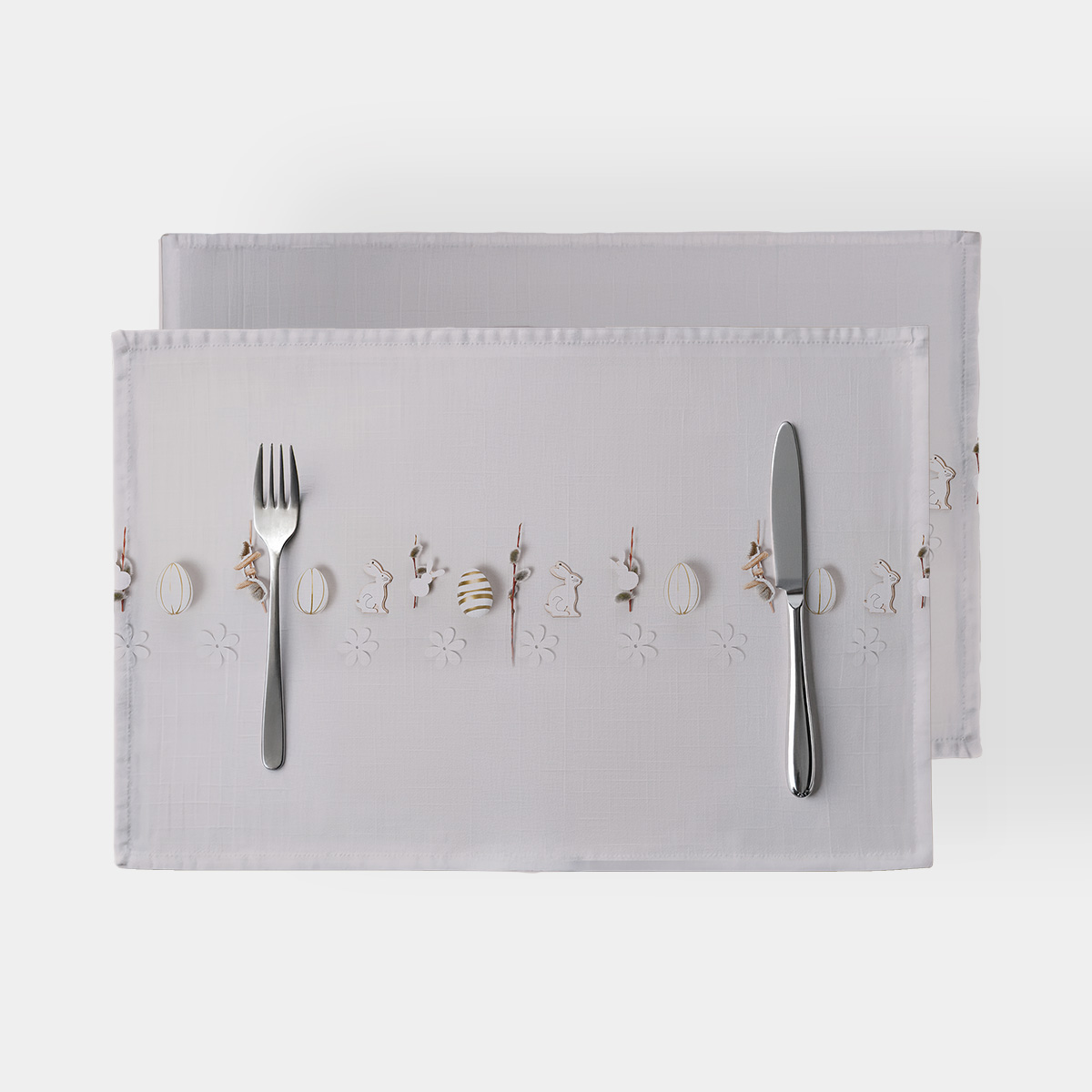 górne ujęcie podkładek na stół z motywem zajączków i pisanek oraz widocznymi sztućcami