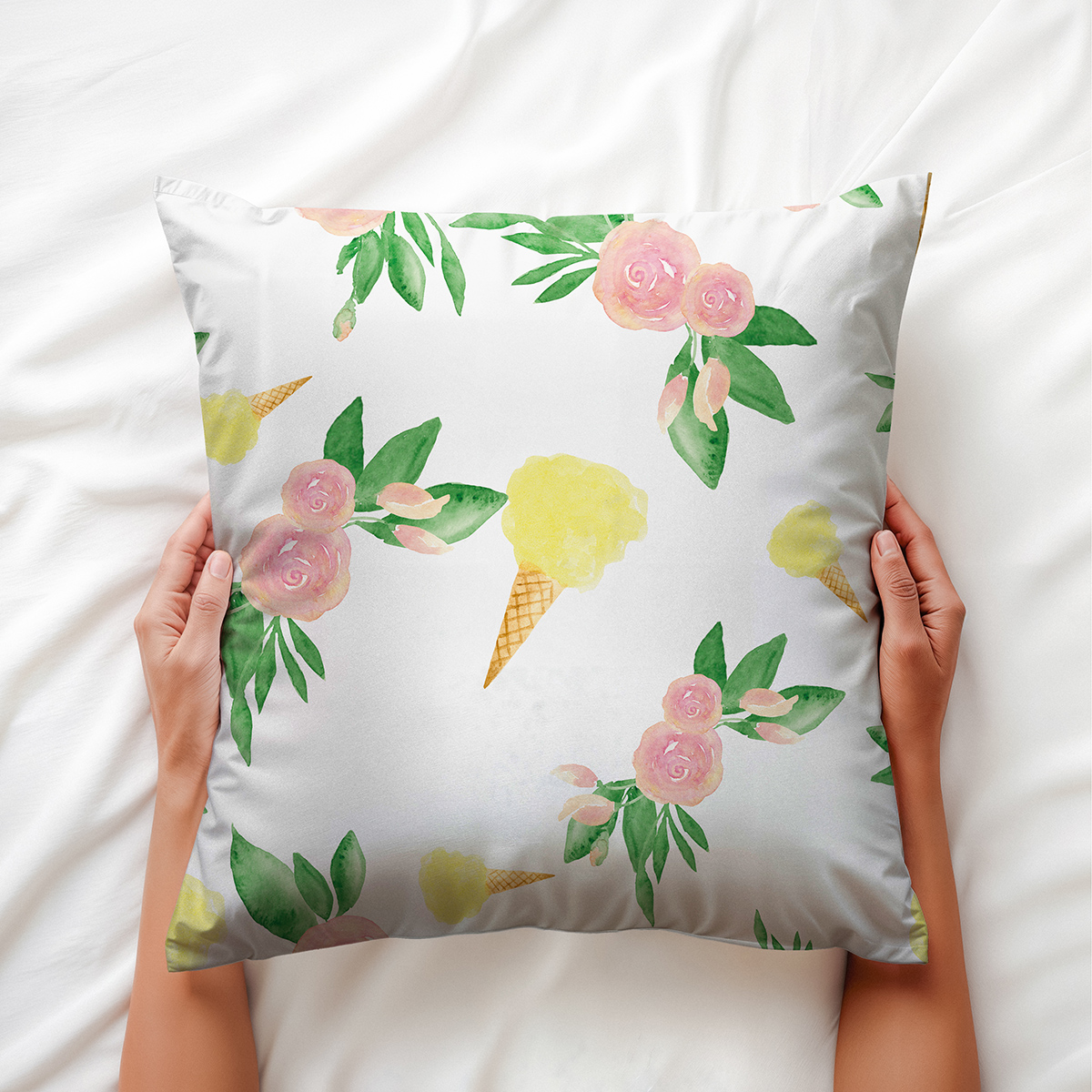 Poduszka ozdobna trzymana w dłoniach, zbliżenie na akwarelowy motyw róż i lodów