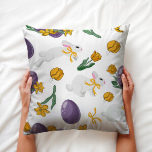 Górne ujęcie poduszki trzymanej dłońmi z widocznym wzorem z zajączkami i fioletowymi jajkami