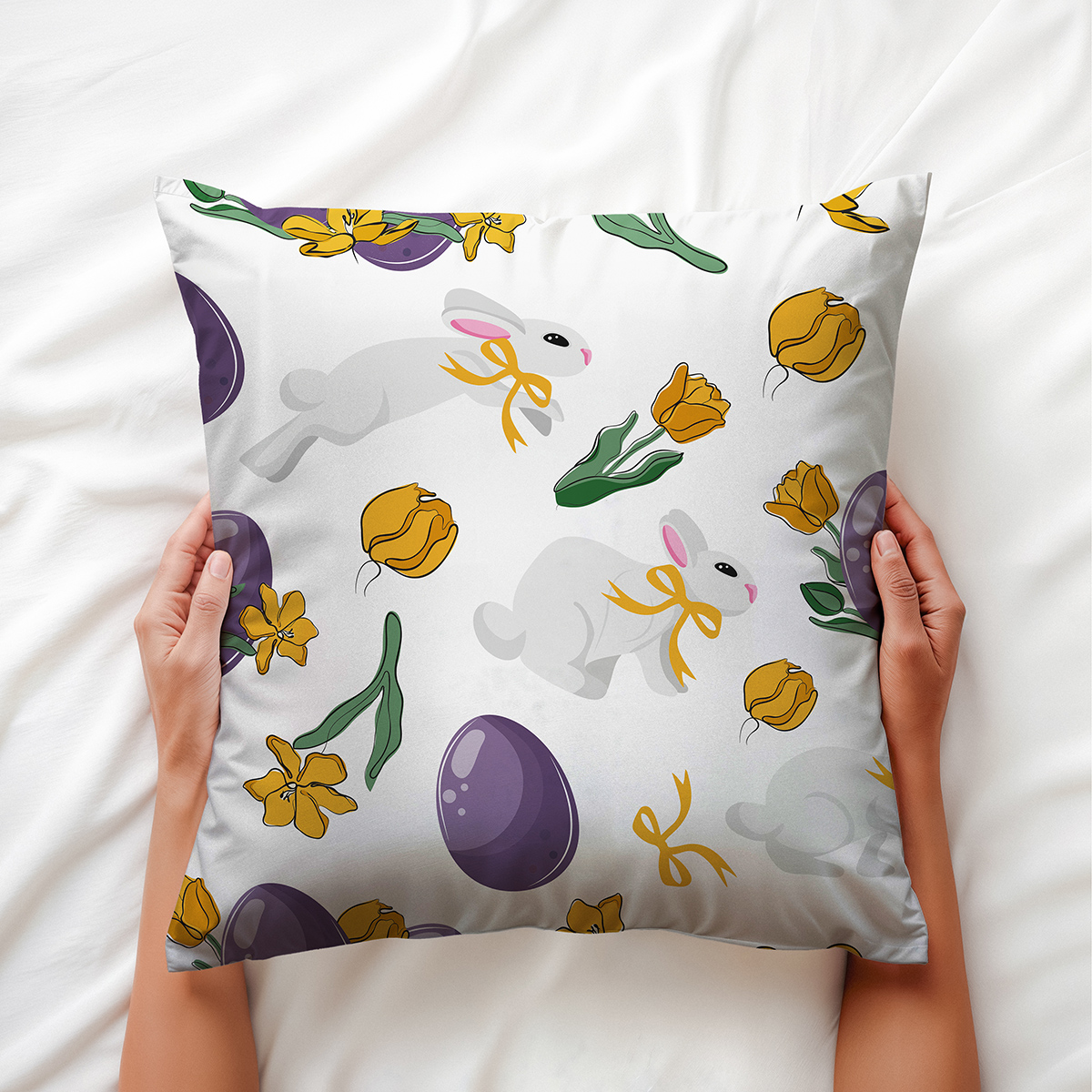 Górne ujęcie poduszki trzymanej dłońmi z widocznym wzorem z zajączkami i fioletowymi jajkami