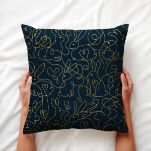 ręce trzymające poduszkę na białej pościeli, widoczny złoty motyw króliczków