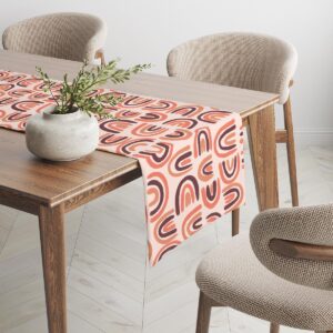 Bieżnik ułożony na drewnianym stole z ceramiczną dekoracją i neutralnymi krzesłami