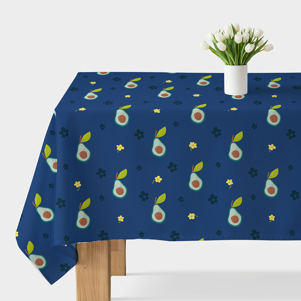 Stół przykryty granatowym obrusem z wzorem awokado i małych żółtych kwiatków