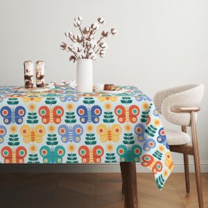 Widok obrusu na stole w jasnym wnętrzu, powtarzalny wzór motyli w różnych kolorach