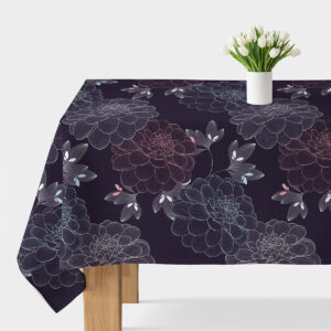 Obrus z granatowym tłem i dużymi konturowymi kwiatami ułożony na stole z wazonem białych kwiatów