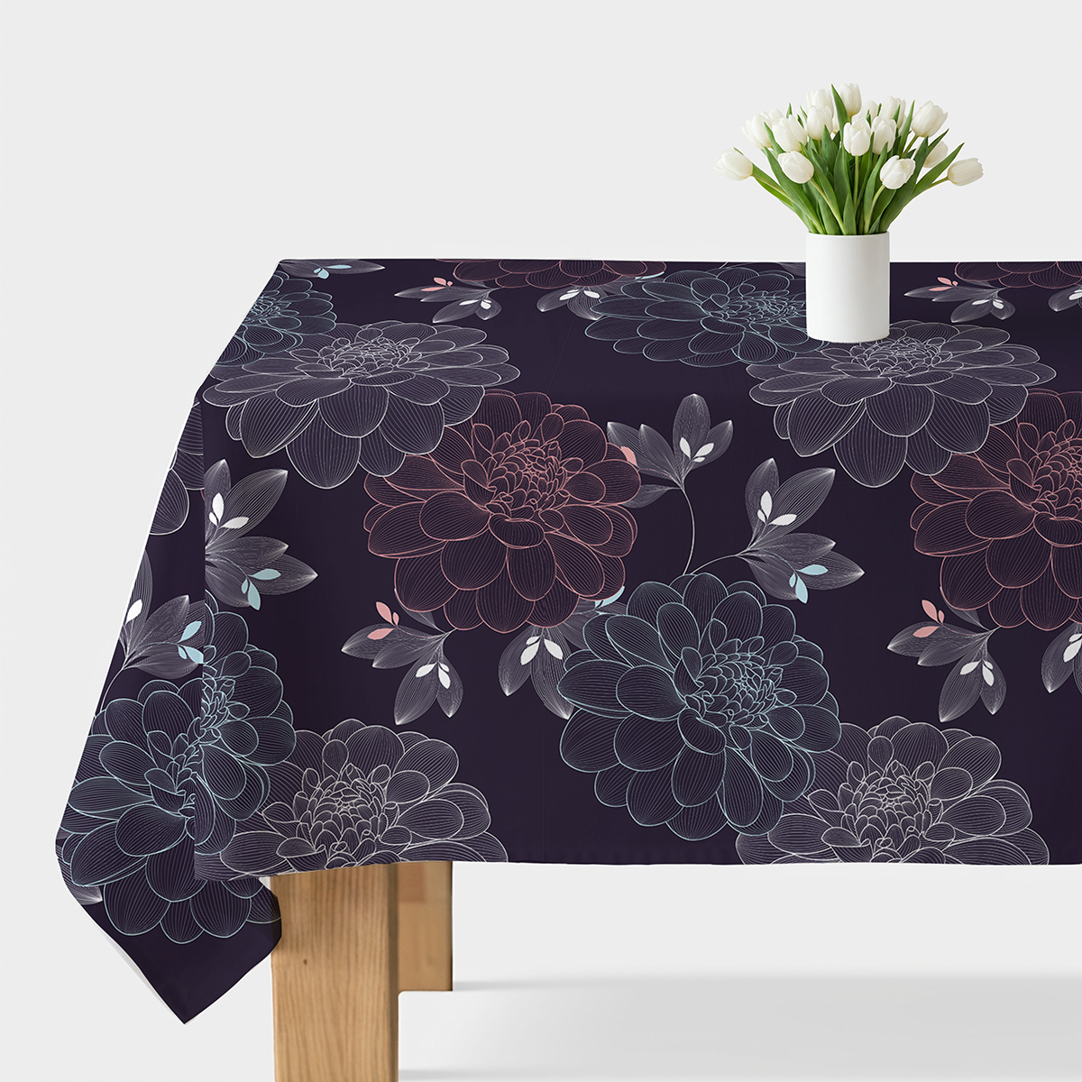 Obrus z granatowym tłem i dużymi konturowymi kwiatami ułożony na stole z wazonem białych kwiatów