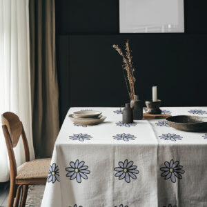 aranżacja stołu z talerzami i ceramicznymi naczyniami na obrusie ze stokrotkami