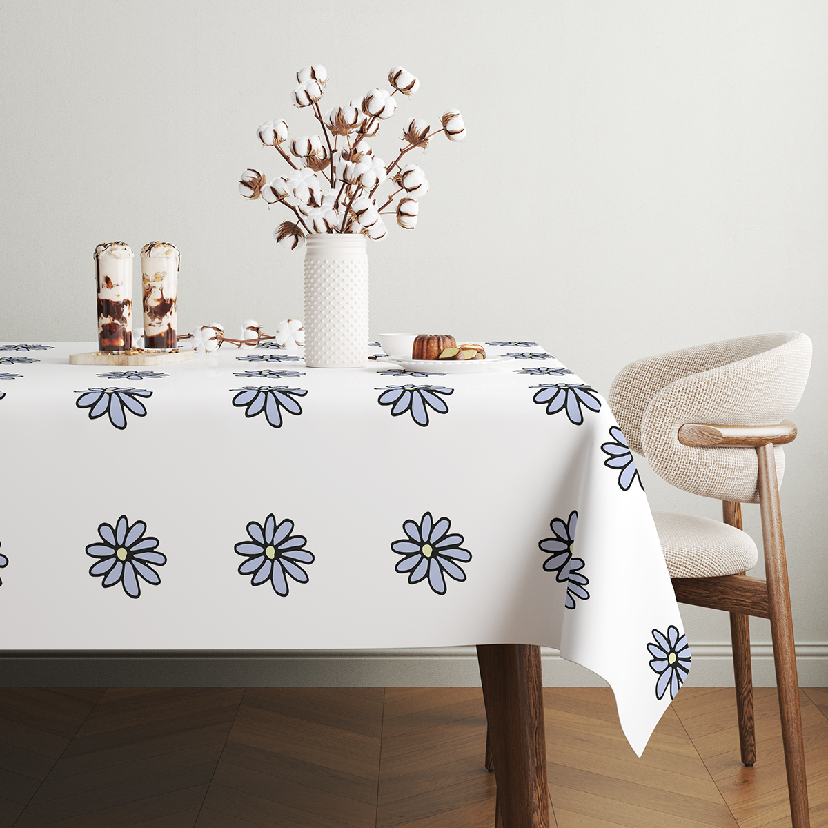 stół udekorowany gałązkami bawełny i obrus z powtarzalnym motywem stokrotek
