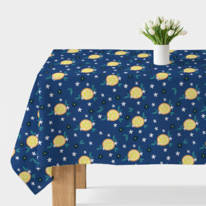 Obrus z motywem cytryn na granatowym tle rozłożony na stole z wazonem tulipanów