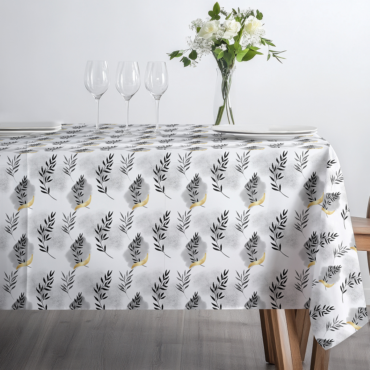 stół nakryty obrusem z trzema kieliszkami i minimalistyczną dekoracją